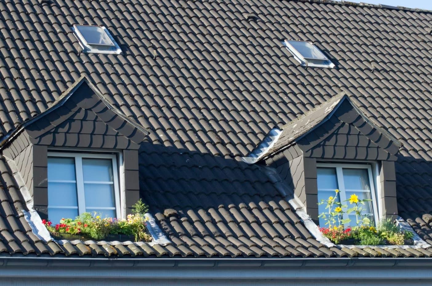 Dark tile roof with two dormer windows and flower boxes