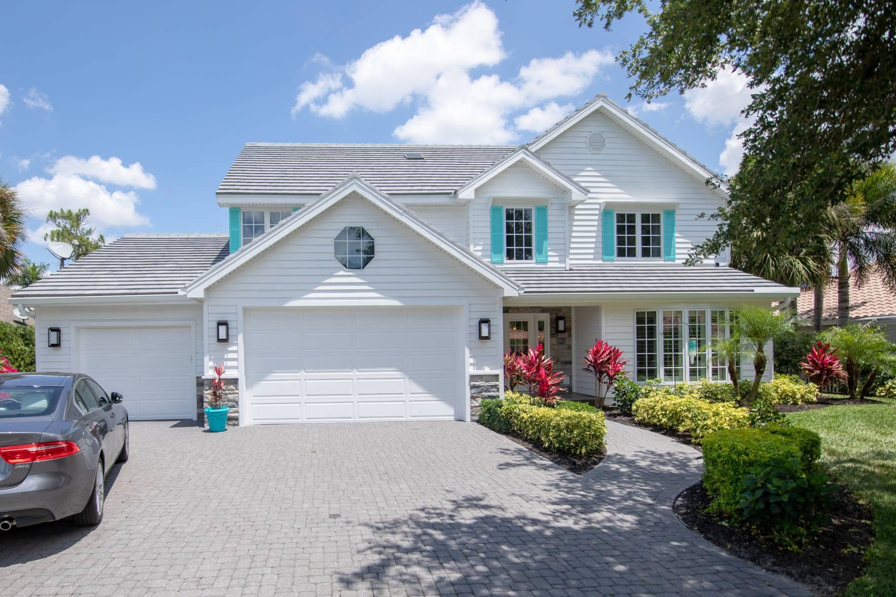 White two story home with grey tile roof and teal shutters